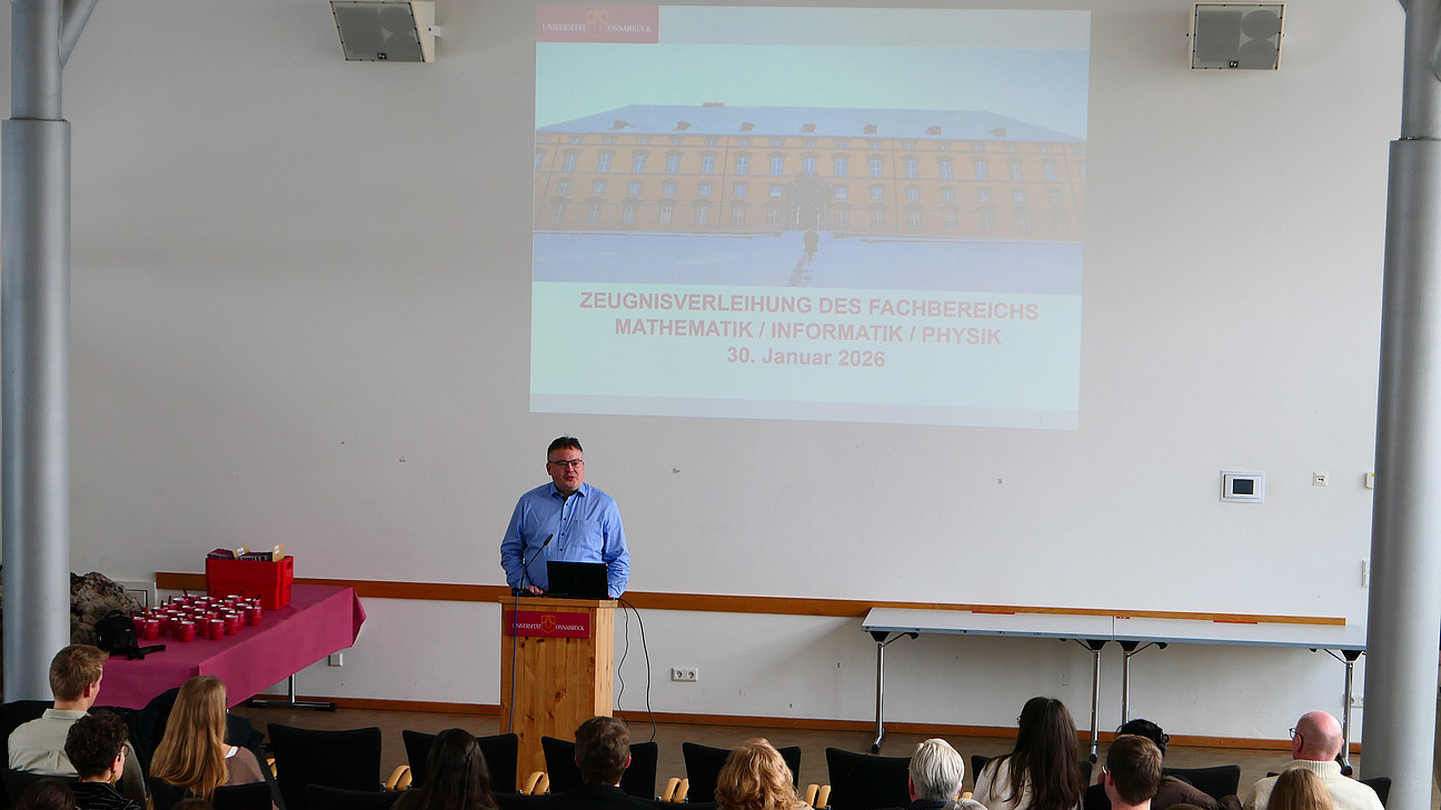 Ein Mann steht an einem Rednerpult. Hinter ihm die Projektion des Osnabr&uuml;cker Schlosses im Schnee.