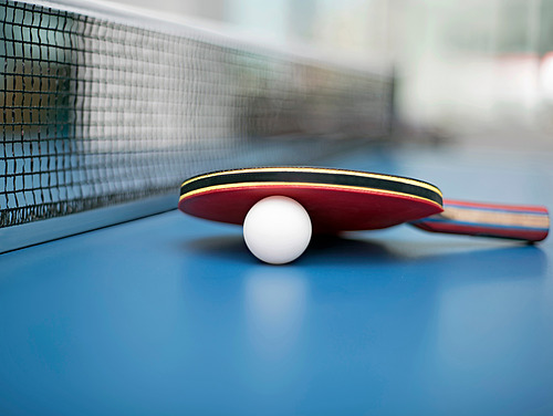 A table tennis bat and a ball are lying on a table tennis table. 