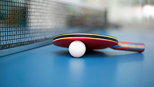 A table tennis bat and a ball are lying on a table tennis table. 