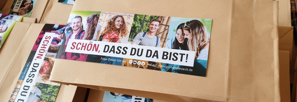 Papiertüten mit einem Aufkleber der Studierende zeigt, darüber der Text: "Schön, dass du da bist".