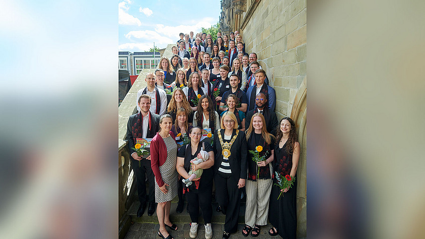 A group of festively dressed people stand on the steps of a historic building
