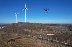 Drohne fliegt über dem Osnabrücker Piesberg, im Hintergrund zwei Windräder