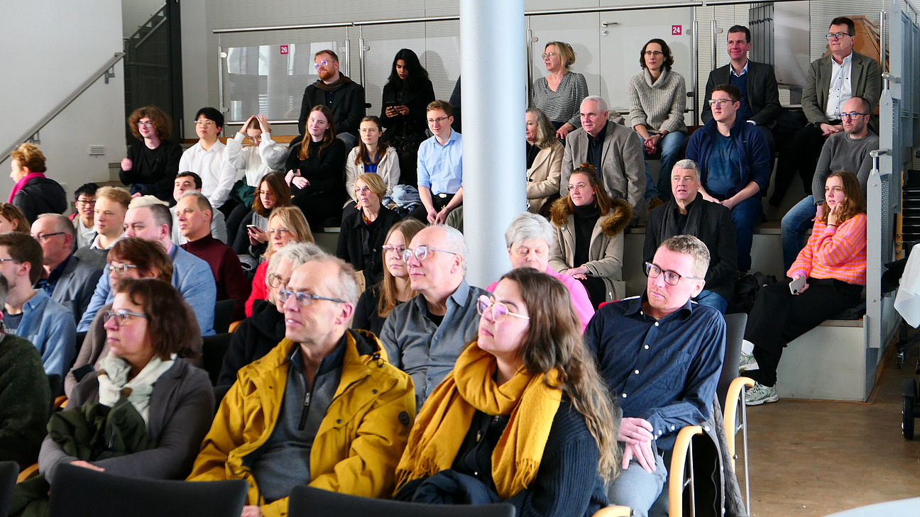 Viele Personen sitzen in Stuhlreihen.