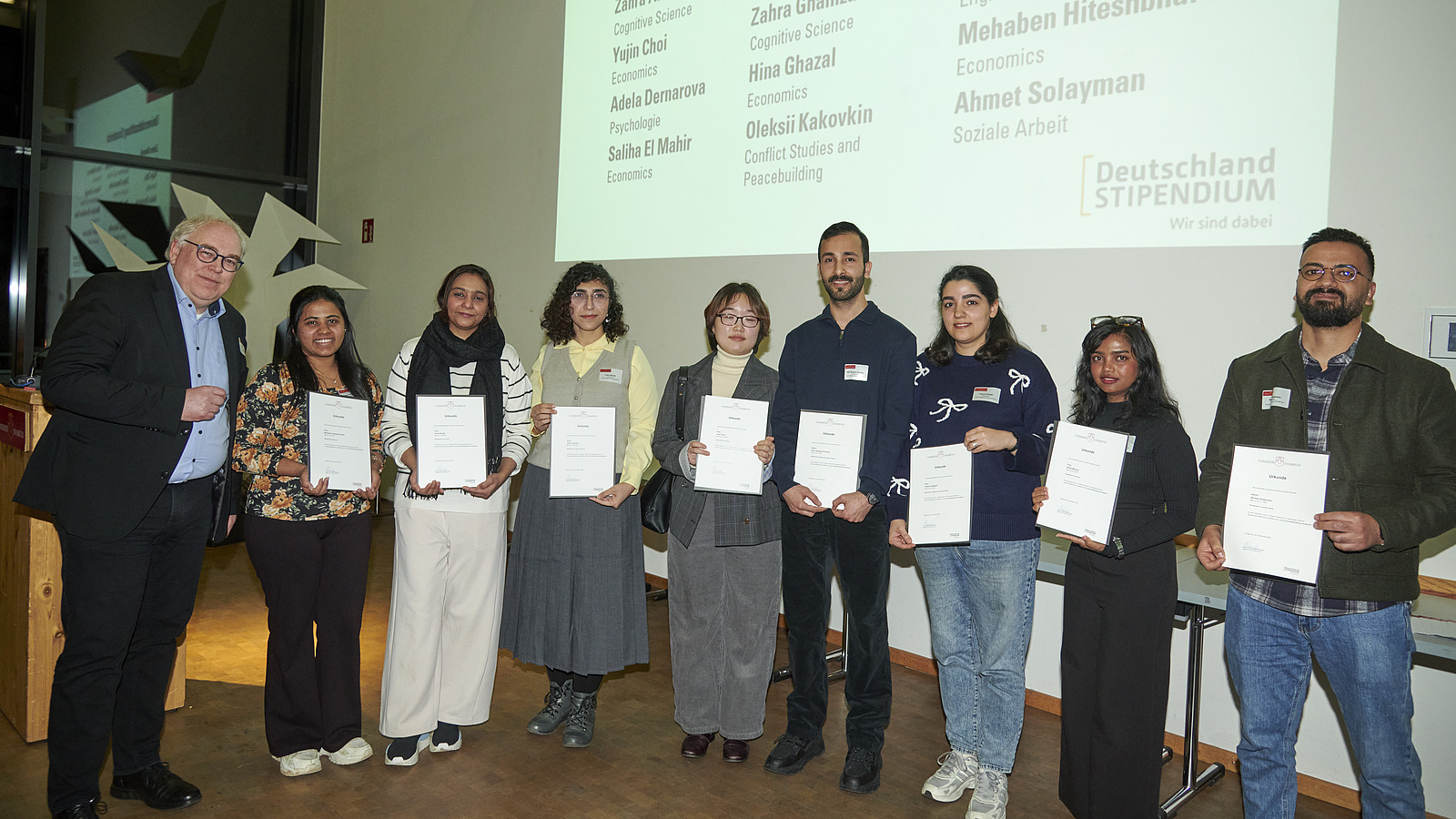 Mehrere Personen auf Bühne bei Urkundenübergabe