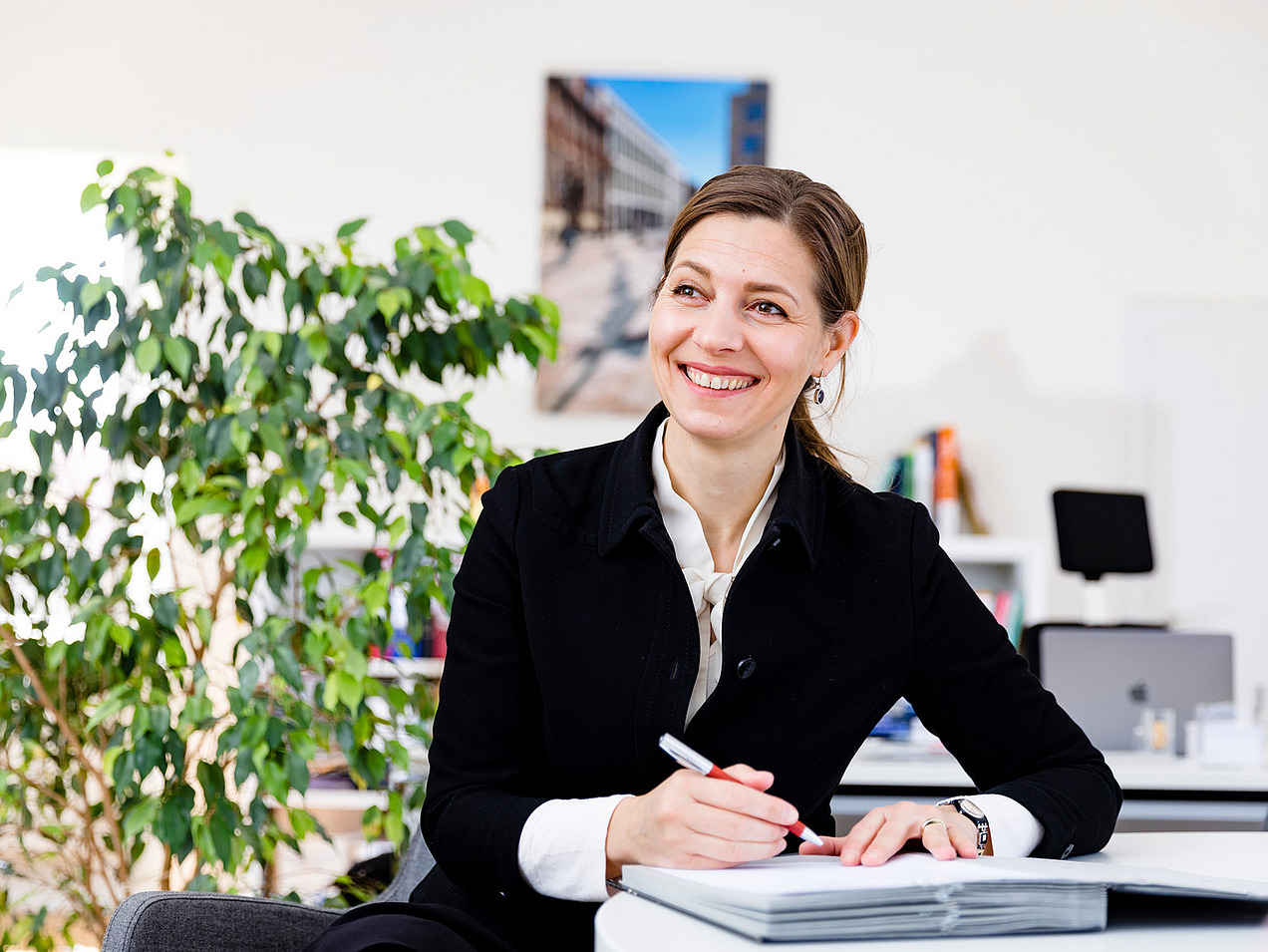 A woman at a desk smiles at the camera.