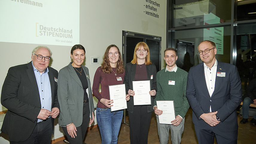 Mehrere Personen auf Bühne bei Urkundenübergabe