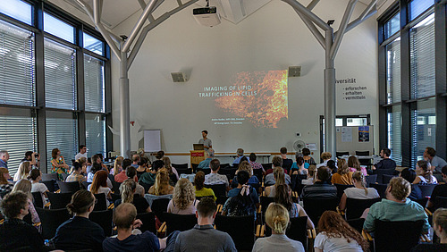 Ein Mann steht vor einem Publikum an einem Rednerpult.