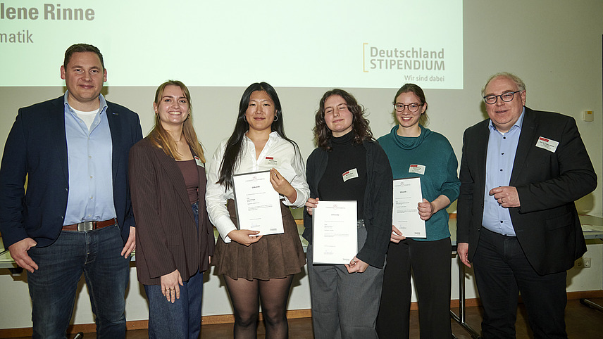 Mehrere Personen auf Bühne bei Urkundenübergabe