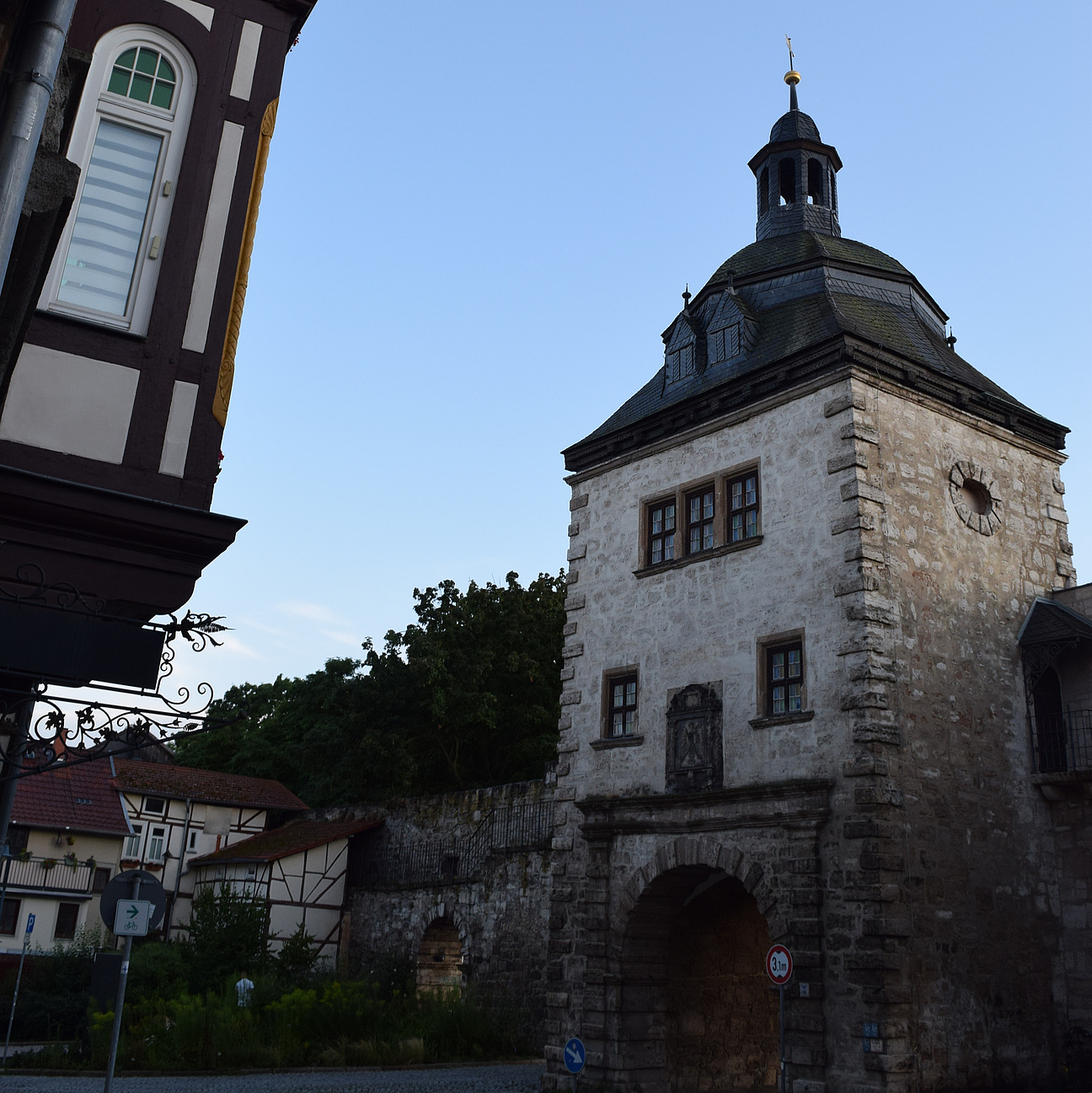 Das Bild zeigt ein helles Stadttor neben der Stadtmauer vor der Stadtseite aus.