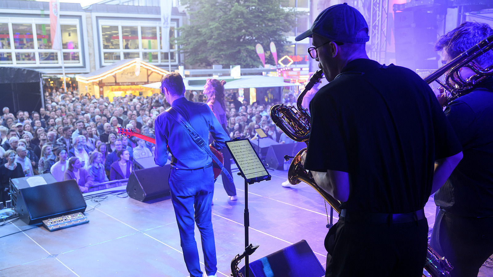 Several musicians on a stage, audience in the background