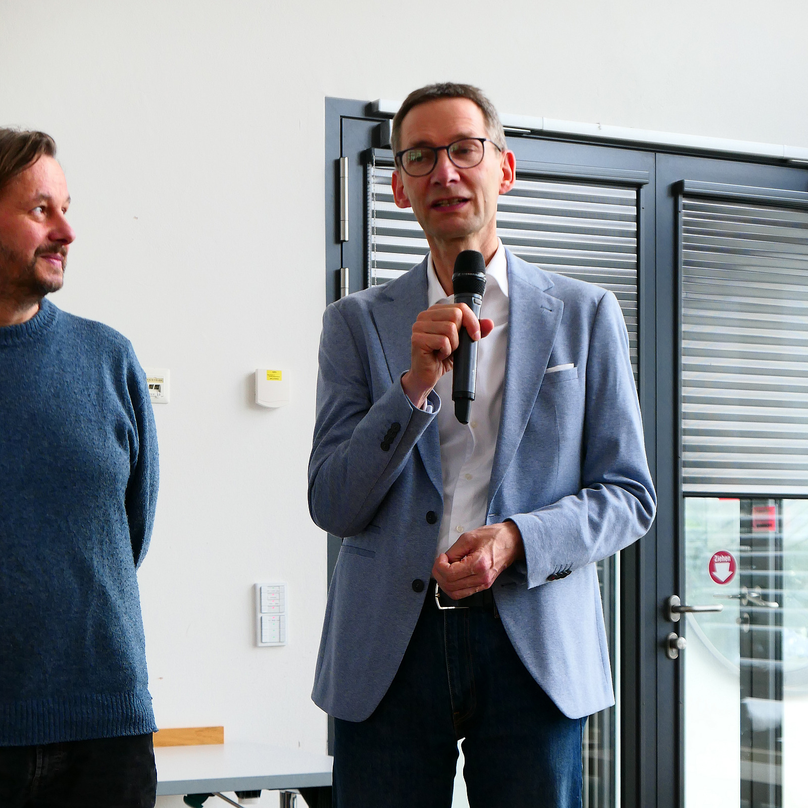 Ein Dozent h&auml;lt ein Mikrofon in der Hand.