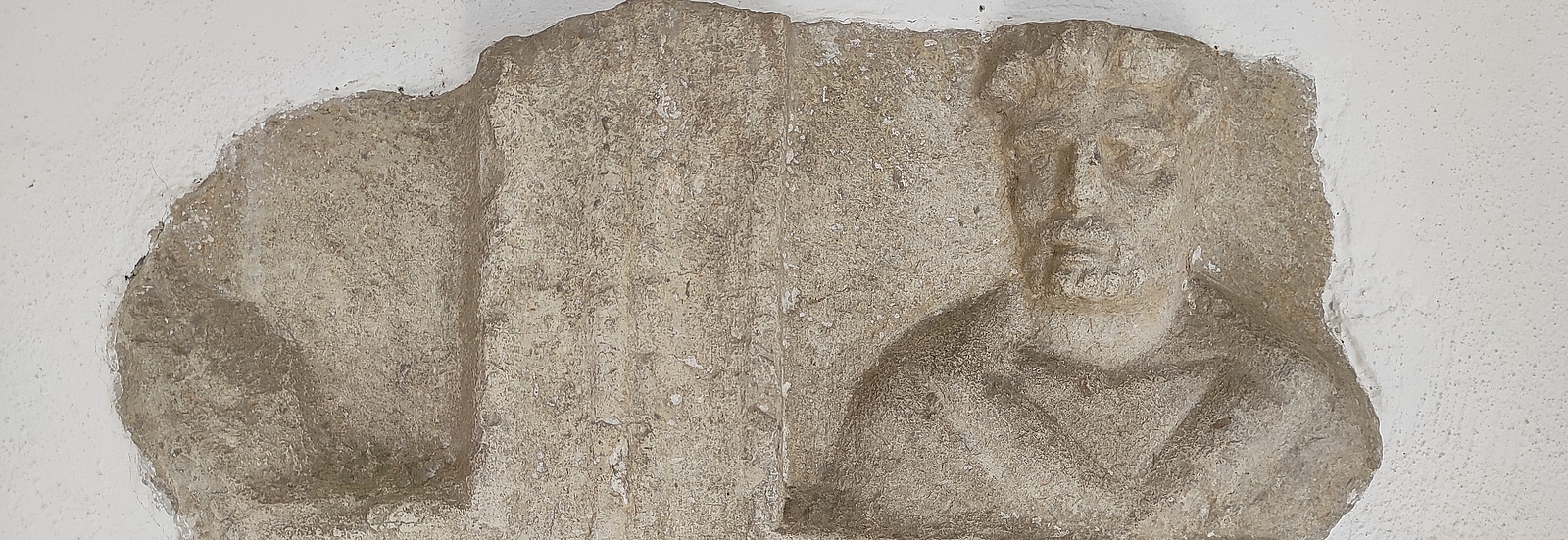 Das Foto zeigt ein fragmentiertes r&ouml;misches Grabmal, eingemauert in eine Kirche