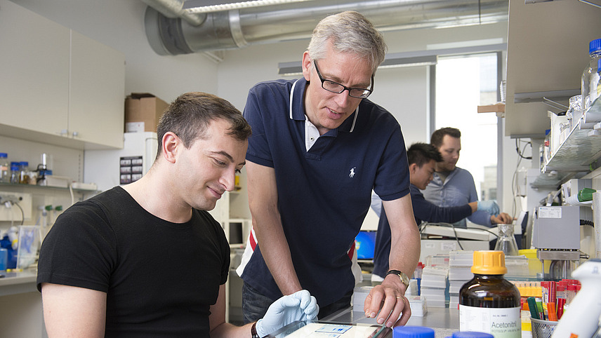  Three students carry out tests in a laboratory. One student is supervised by the professor. 