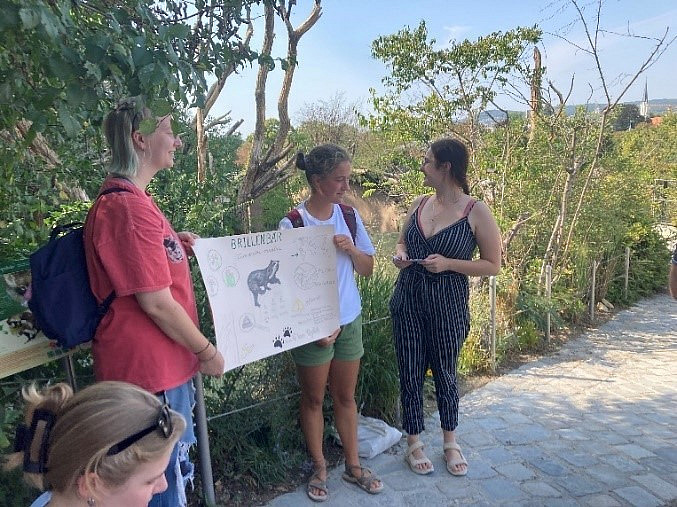 Two people are standing in the zoo holding a poster.
