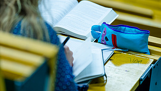 Eine Studentin schreibt etwas in ein kleies Buch während einer Vorlesung.