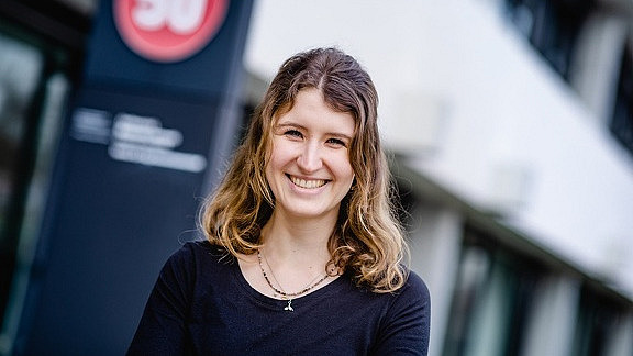 young woman with long hair smiles into the camera