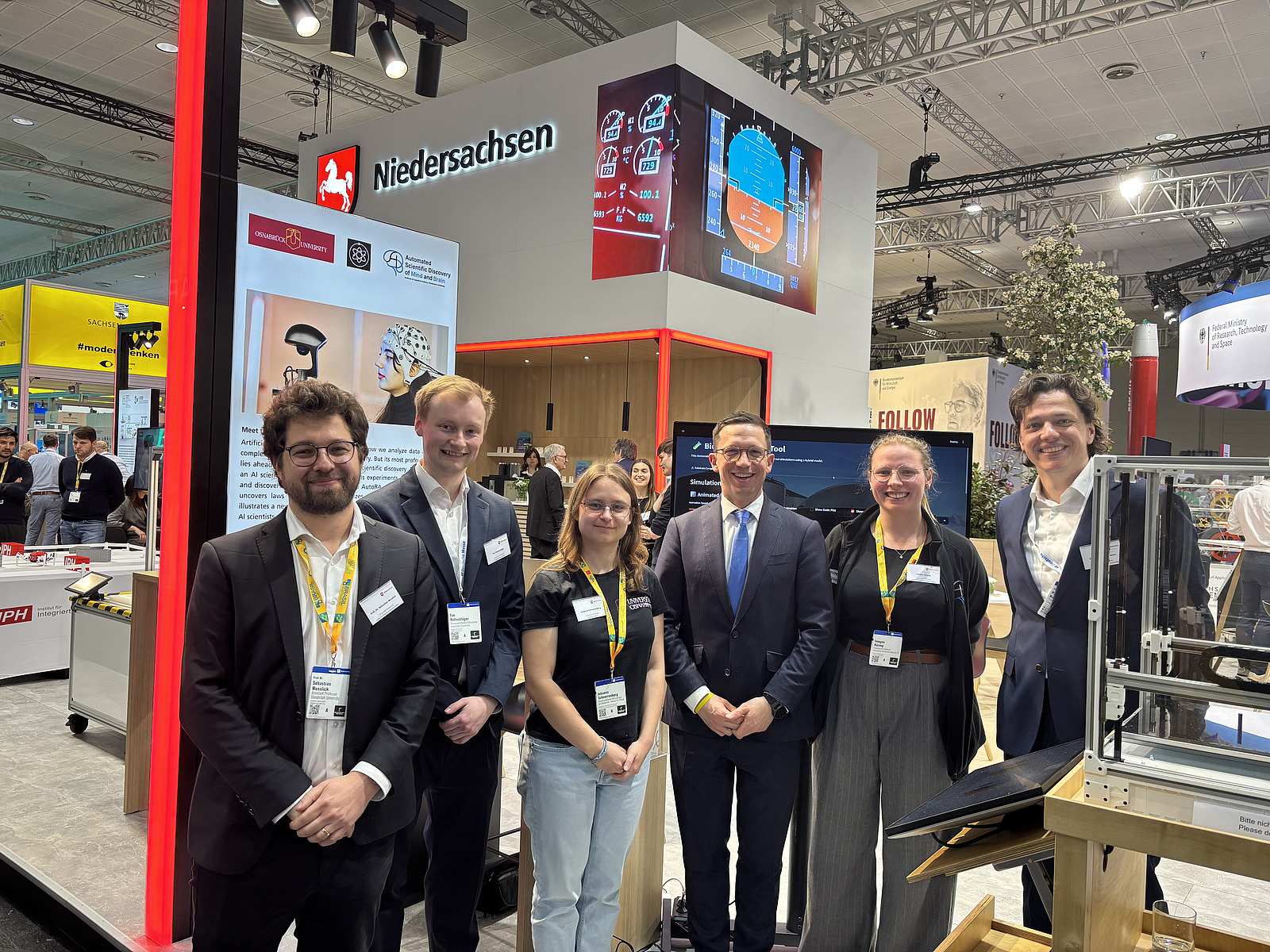 Two women and three men stand in front of an exhibition stand. 