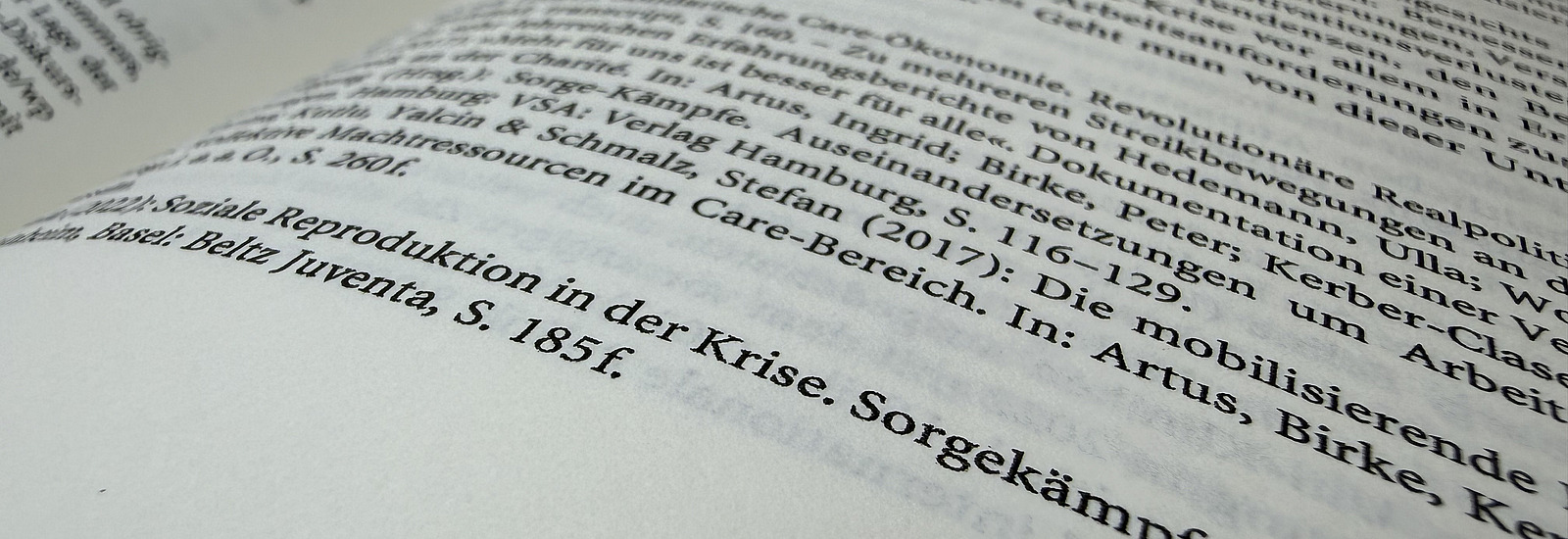 Nahaufnahme eines aufgeschlagenen Fachbuchs mit deutschsprachigem Flie&szlig;text; Fokus liegt auf einer Seite mit Literaturangaben.