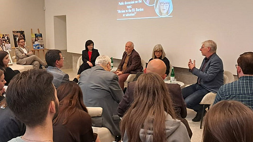 Panel discussion in Chernivtsi Panel discussion in Chernivsti: Ulrich Schneckener and three other speaker sit on a small stage. In the front, guests are sitting close to each other and are taking notes.