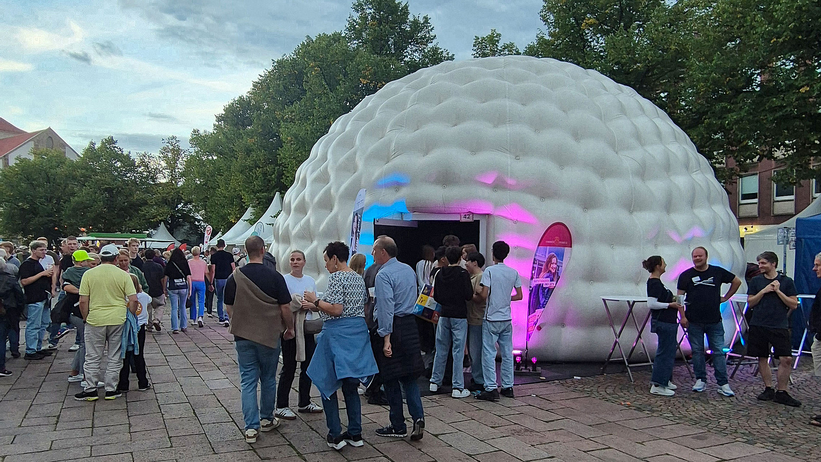 An illuminated dome attracts people in a public square.