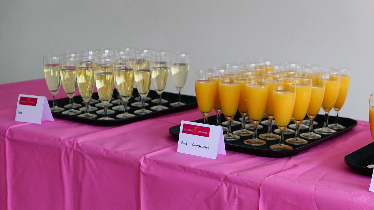 Gl&auml;ser mit Orangensaft und Sekt stehen auf zwei Tabletts auf einem Tisch.