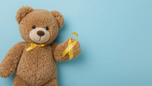 Ein plüschiger Teddy mit einer Schleife vor blauem Hintergrund.
