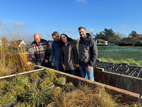 Drei M&auml;nner und eine Frau blicke auf einen Pflanzkasten.