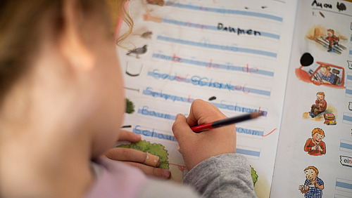 Ein Sch&uuml;ler beugt sich &uuml;ber sein Schreibheft.