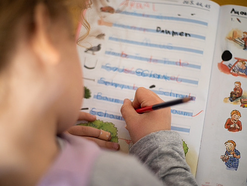 Ein Sch&uuml;ler beugt sich &uuml;ber sein Schreibheft.