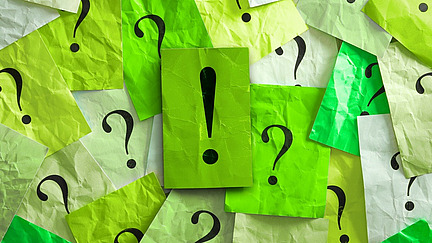 Viele Post-It Zettel mit Fragezeichen und ein Zettel mit Ausrufzeichen 
