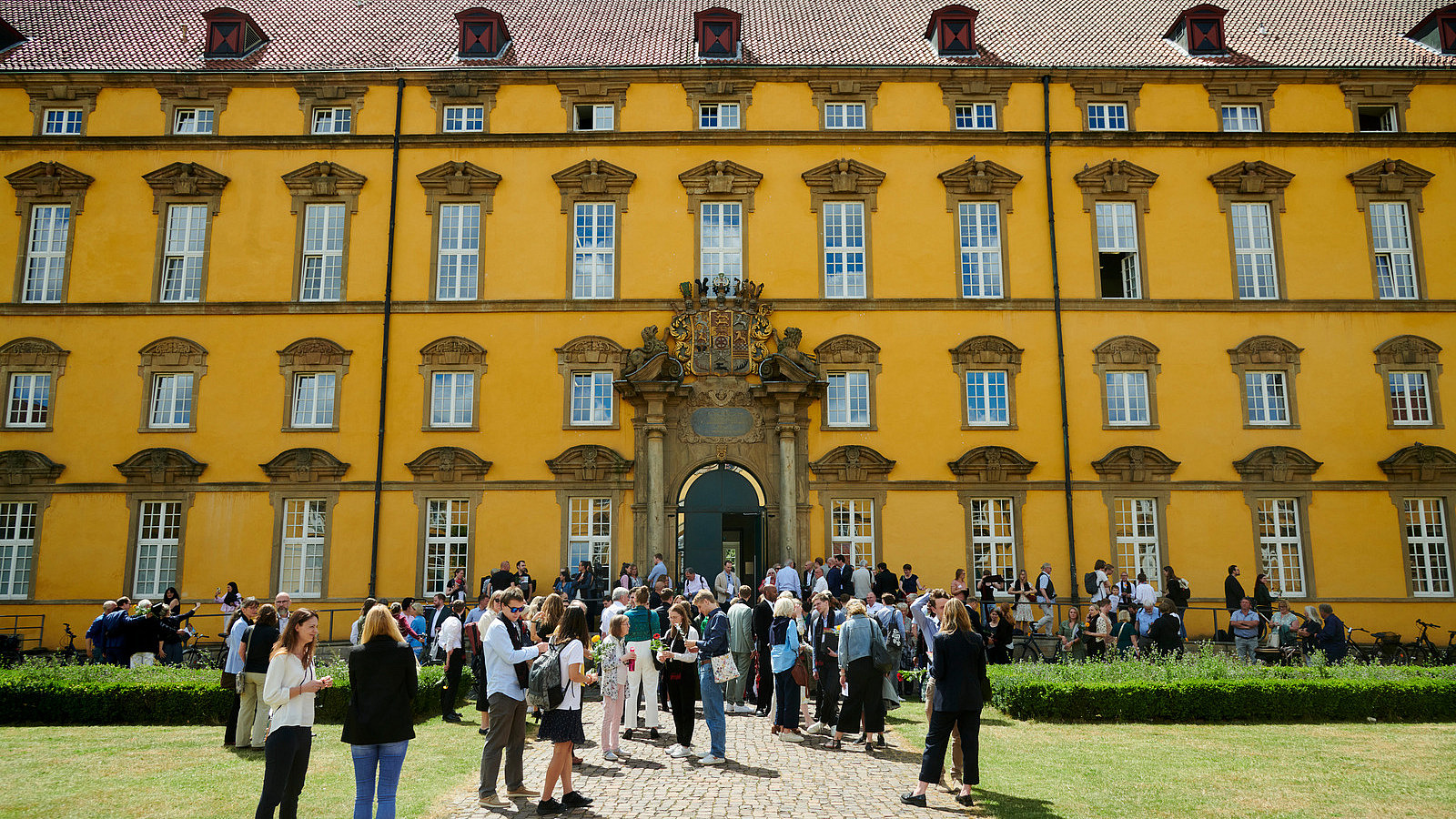 Numerous people stand in front of a historic building.