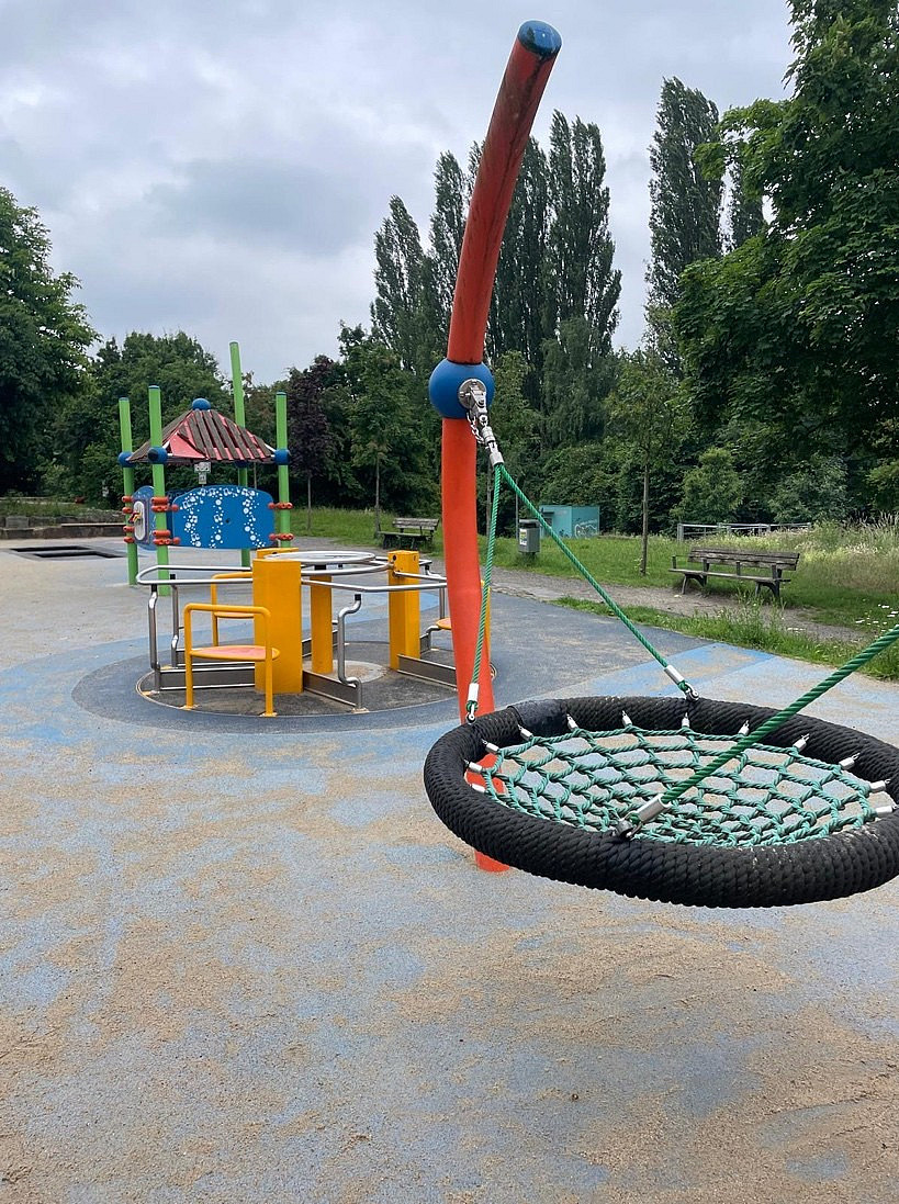 Bunte Spielplatzanlage mit H&auml;uschen, Karussell und Vogelschaukel 