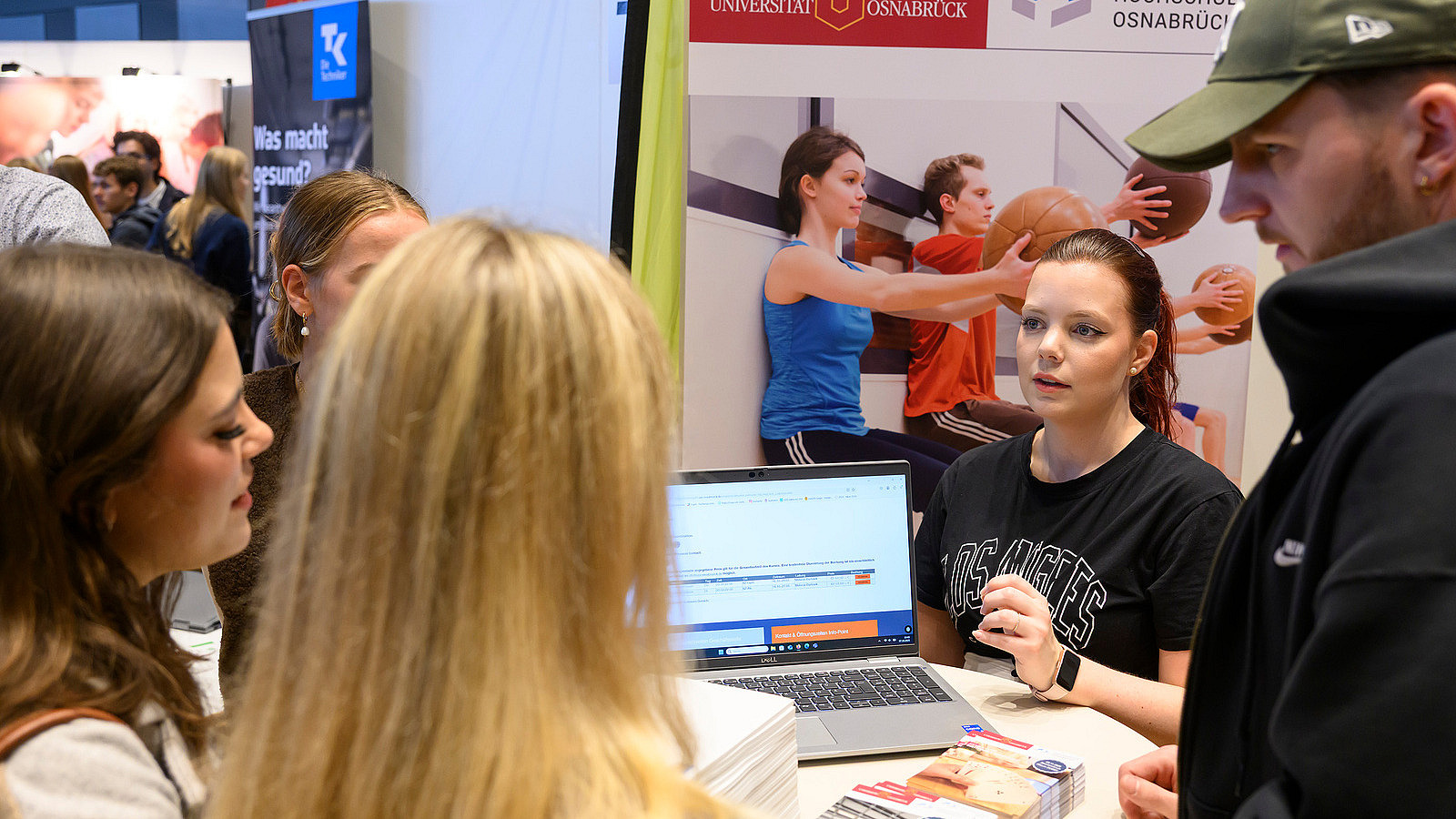 Close-up of an exhibition booth where several people are gathering information