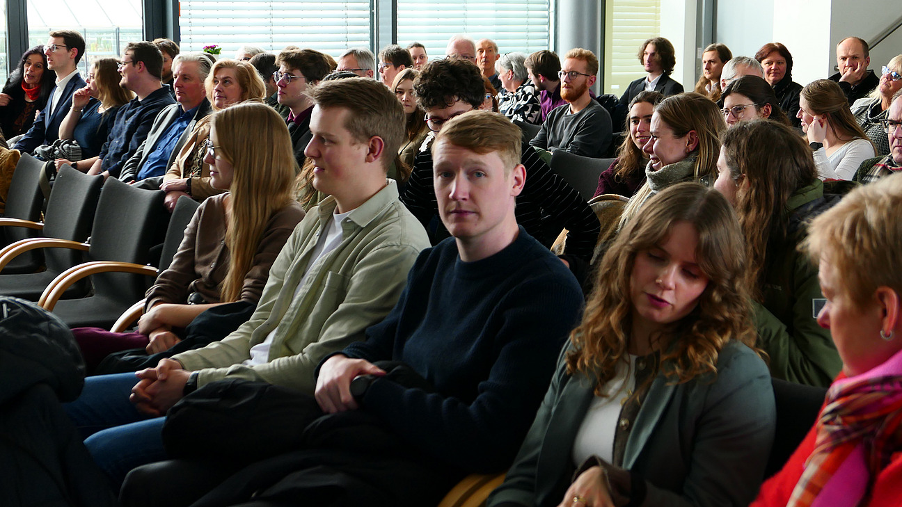 Viele Personen sitzen und Stuhlreihen.
