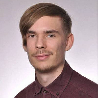 Junger Mann mit kurzen braunen Haaren, schaut in die Kamera.