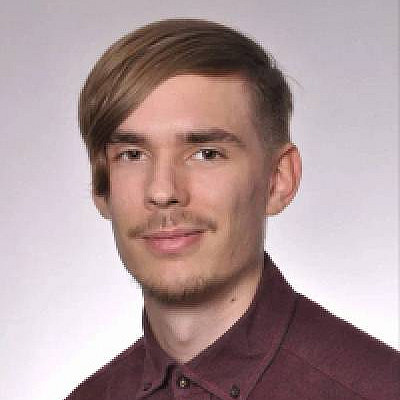 Junger Mann mit kurzen Haaren und burgunderfarbenem Hemd lächelt