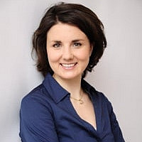 Frau lächelt vor hellem Hintergrund.