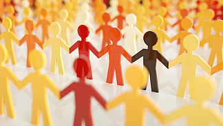 A colorful arrangement of several rows of paper figures holding hands. The figures are arranged in different shades of yellow, orange, red and black.