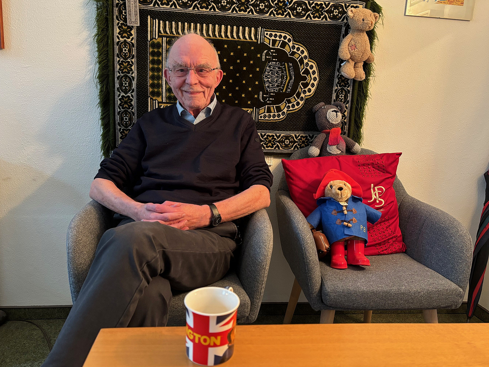 Ein Mann sitzt auf einem Sofa und l&auml;chelt in die Kamera. 