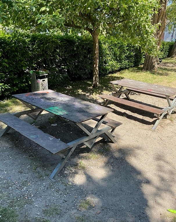 Zwei Gruppentische aus Holz, teilweise mit Graffiti bespr&uuml;ht