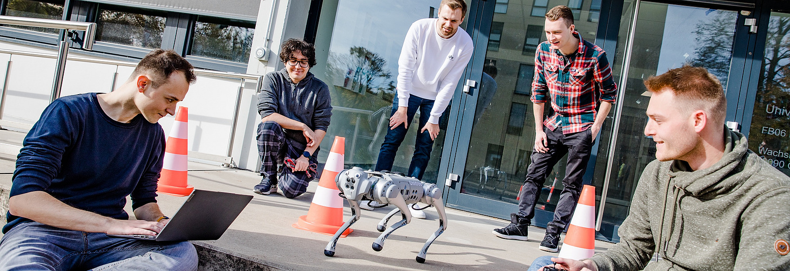 Students and the robodog LESSI in front of the building