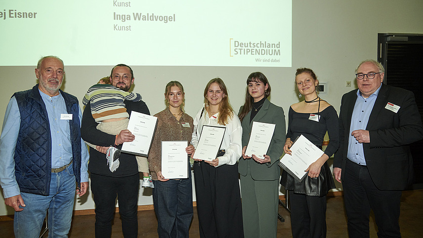 Mehrere Personen auf Bühne bei Urkundenübergabe