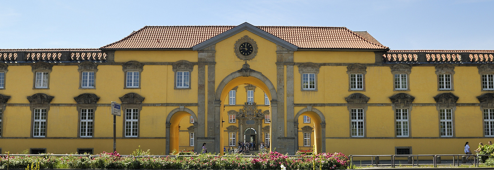 The main gate of the castle with the large clock above the archway. The entrance to the main building is visible through this archway.