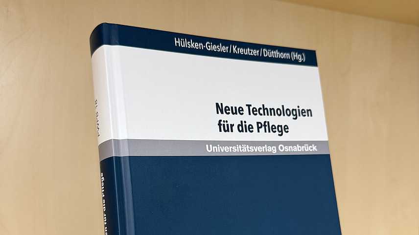 Ein Fachbuch von Manfred H&uuml;lsken-Giesler, Susanne Kreutzer und Nadin D&uuml;tthorn mit dem Titel "Neue Technologien f&uuml;r die Pflege" steht in einem Regal.