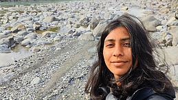 young woman with dark long hair smiles into the camera