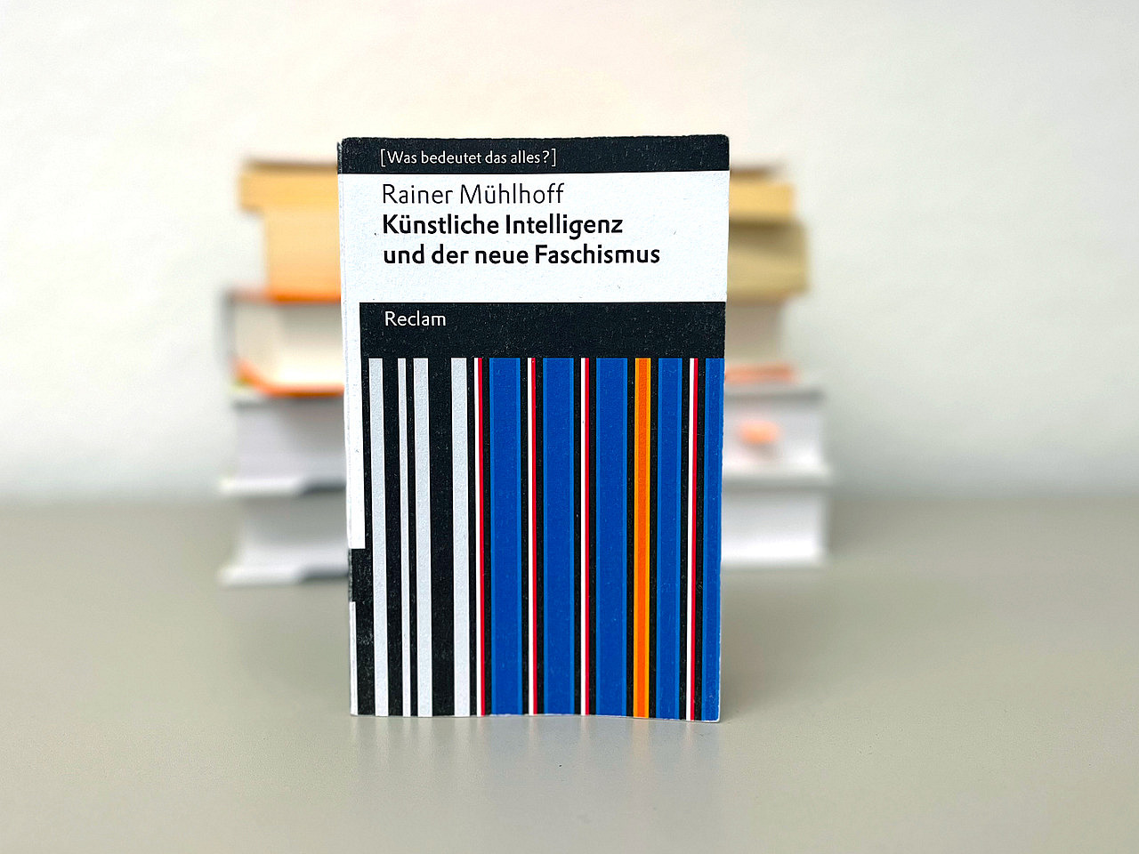Ein Buch mit gestreiftem Cover vor einem B&uuml;cherstapel