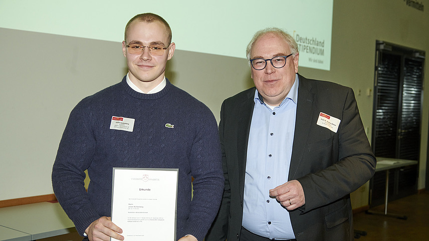 Mehrere Personen auf Bühne bei Urkundenübergabe