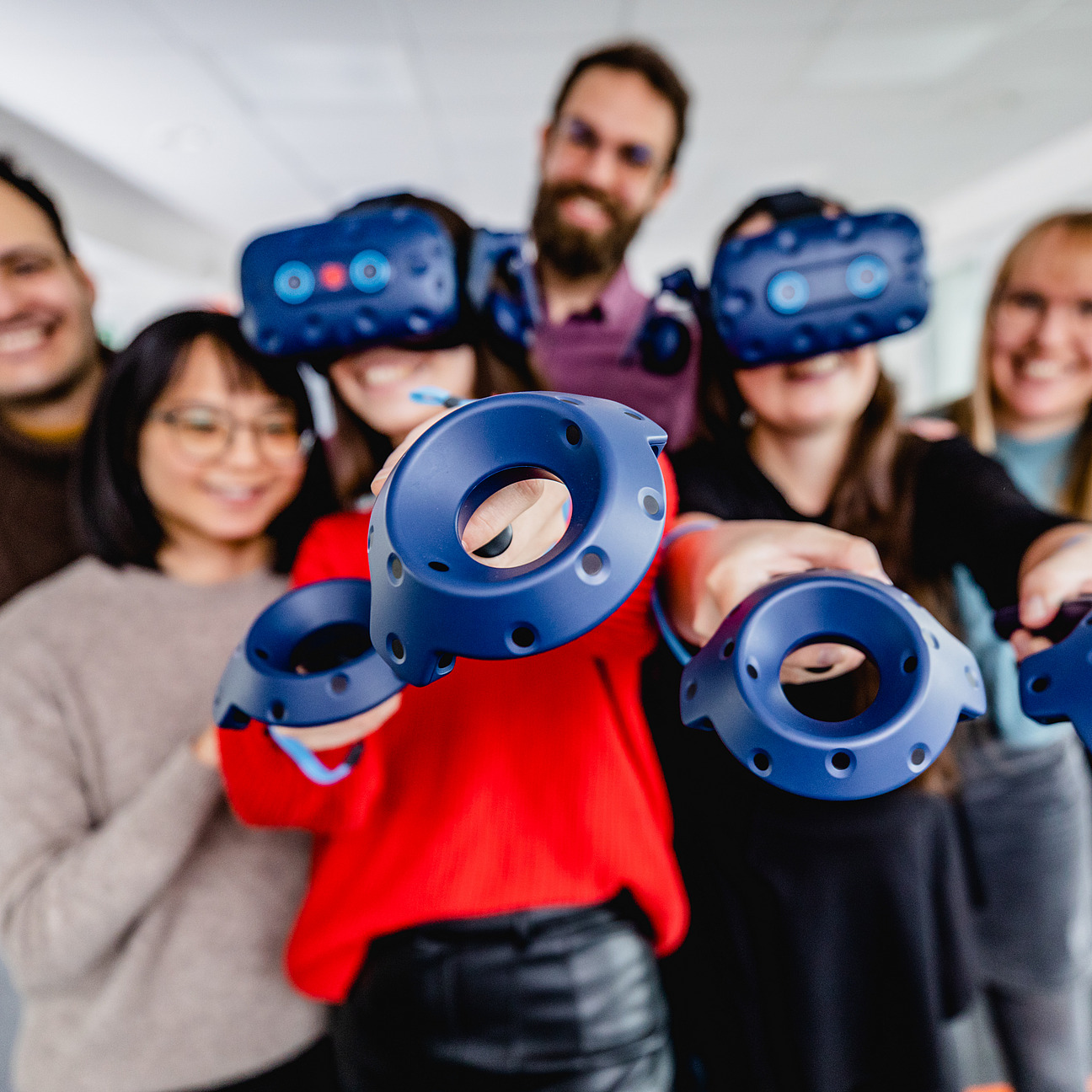 Mehrere Studierende zeigen aus Spaß mit den Virtual Reality Zubehör auf den Zuschauer