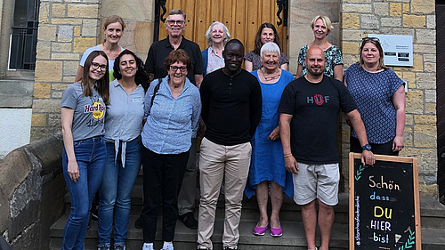 Group photo of people standing in front of a stone building