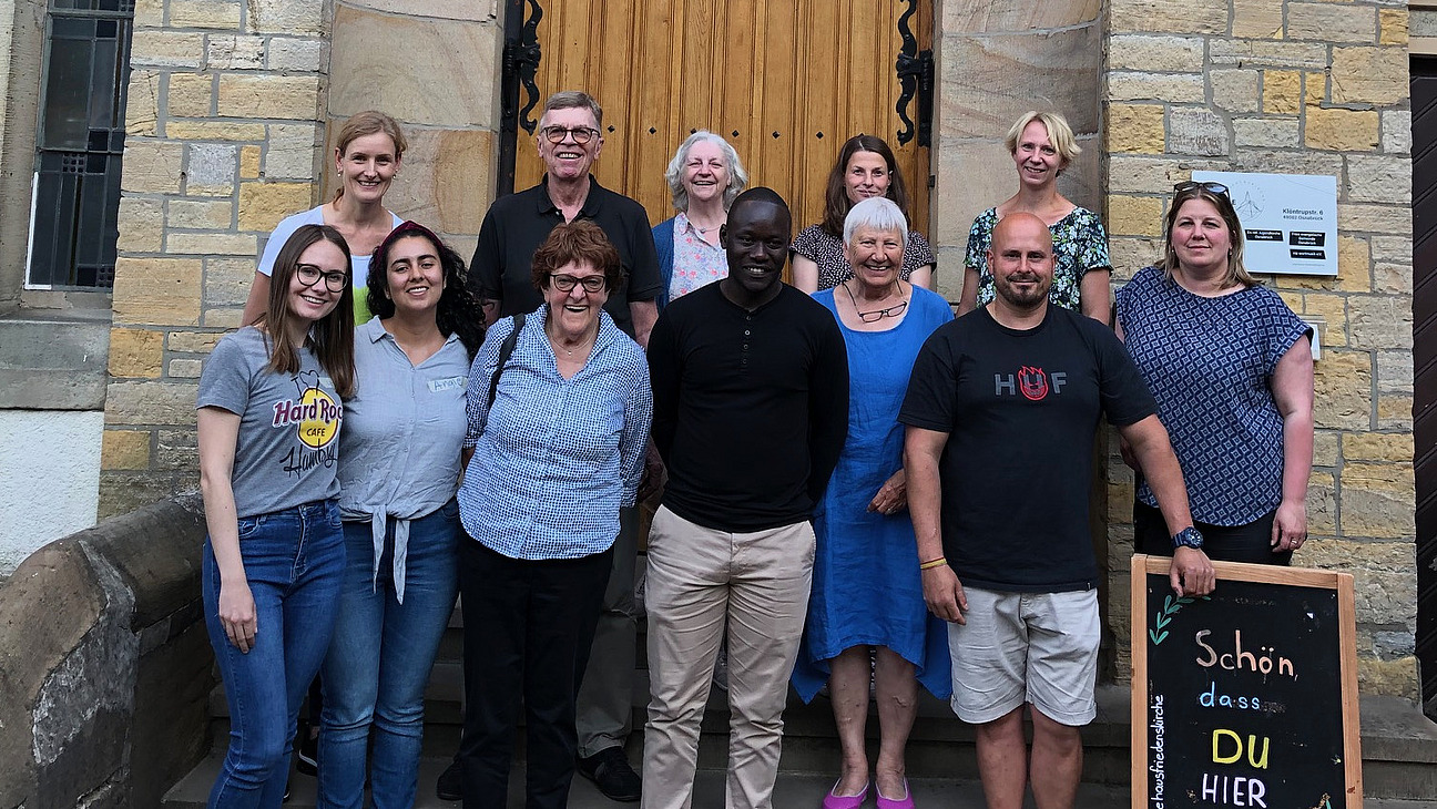 Group photo of people standing in front of a stone building